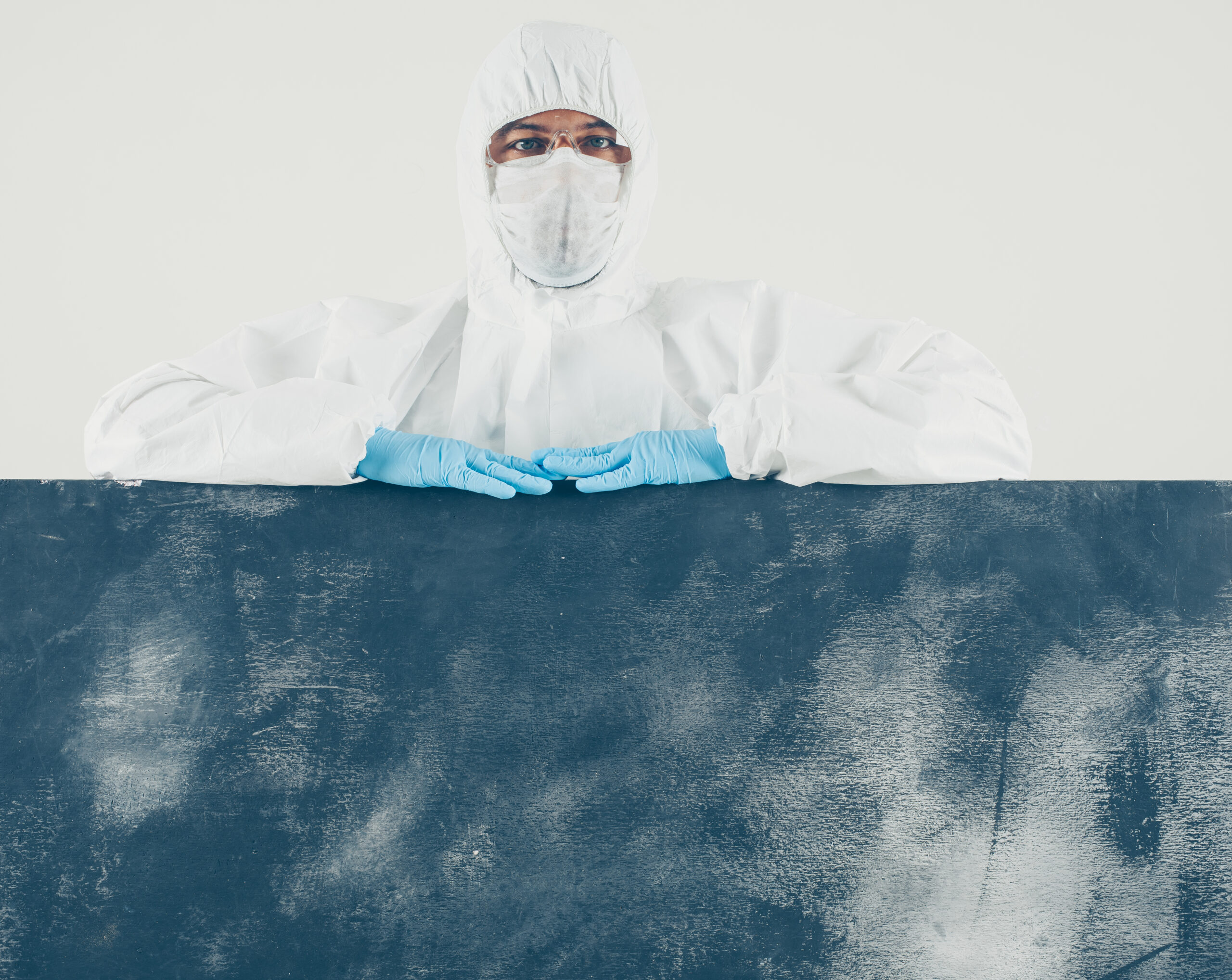 A doctor standing and looking in white and dark background in mask, gloves and protective suit . . space for text. coronavirus